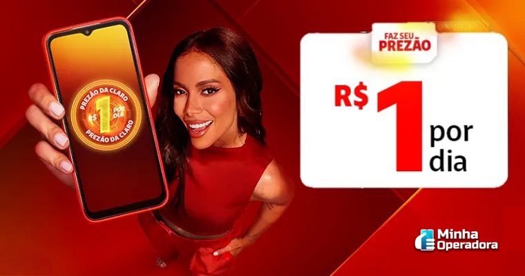 A cantora Anitta aparece sorridente, vestindo uma roupa vermelha, segurando um smartphone. Na tela do celular, aparece o logotipo do Prezão da Claro com o preço de R$ 1 por dia em destaque. Ao lado da mulher, há um banner que reforça a oferta, com o texto: 