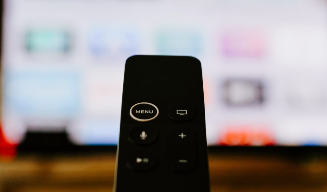 Controle remoto, com TV smart desfocada ao fundo