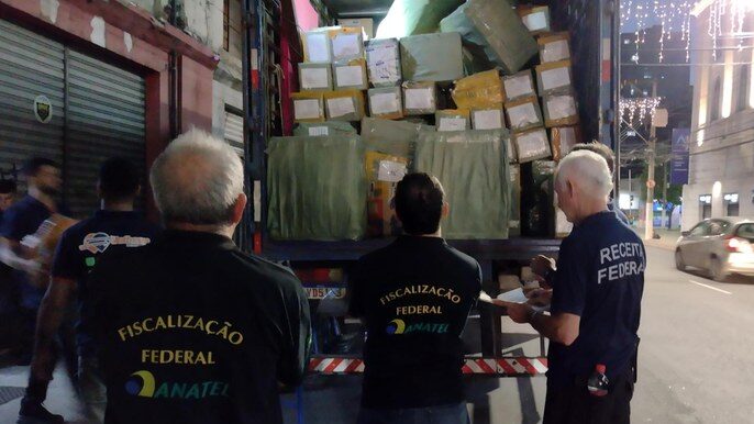 Agendes uniformizados da Anatel e Receita Federal acompanham carregamento de caminhão com mercadorias sem homologação