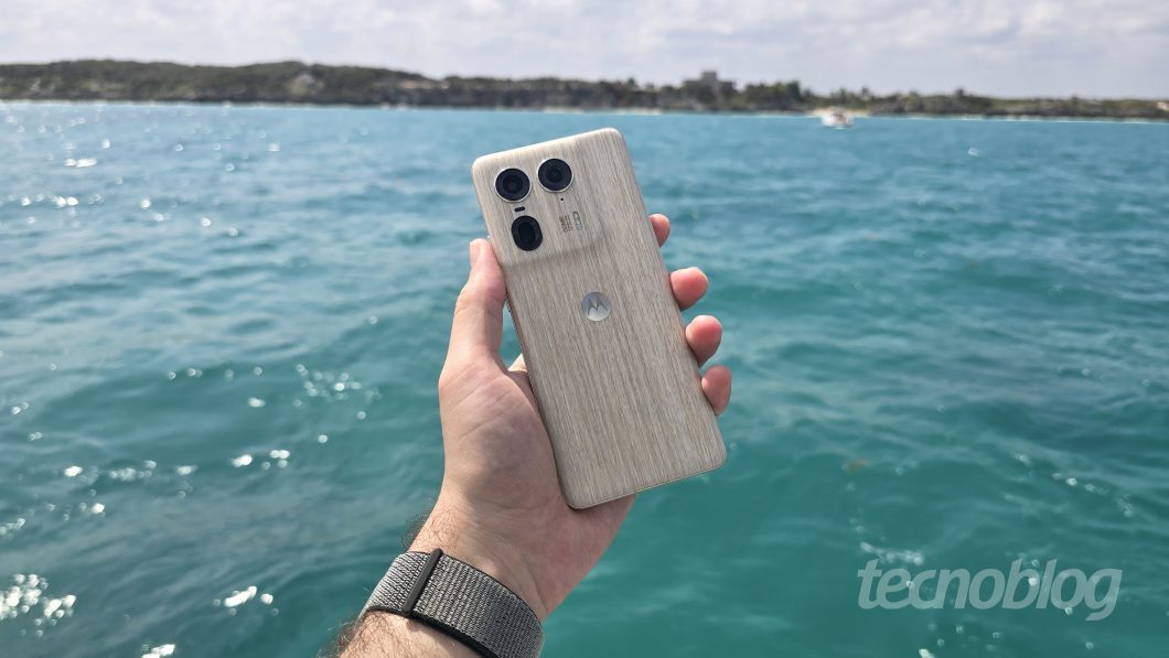 Mão segurando celular de costas