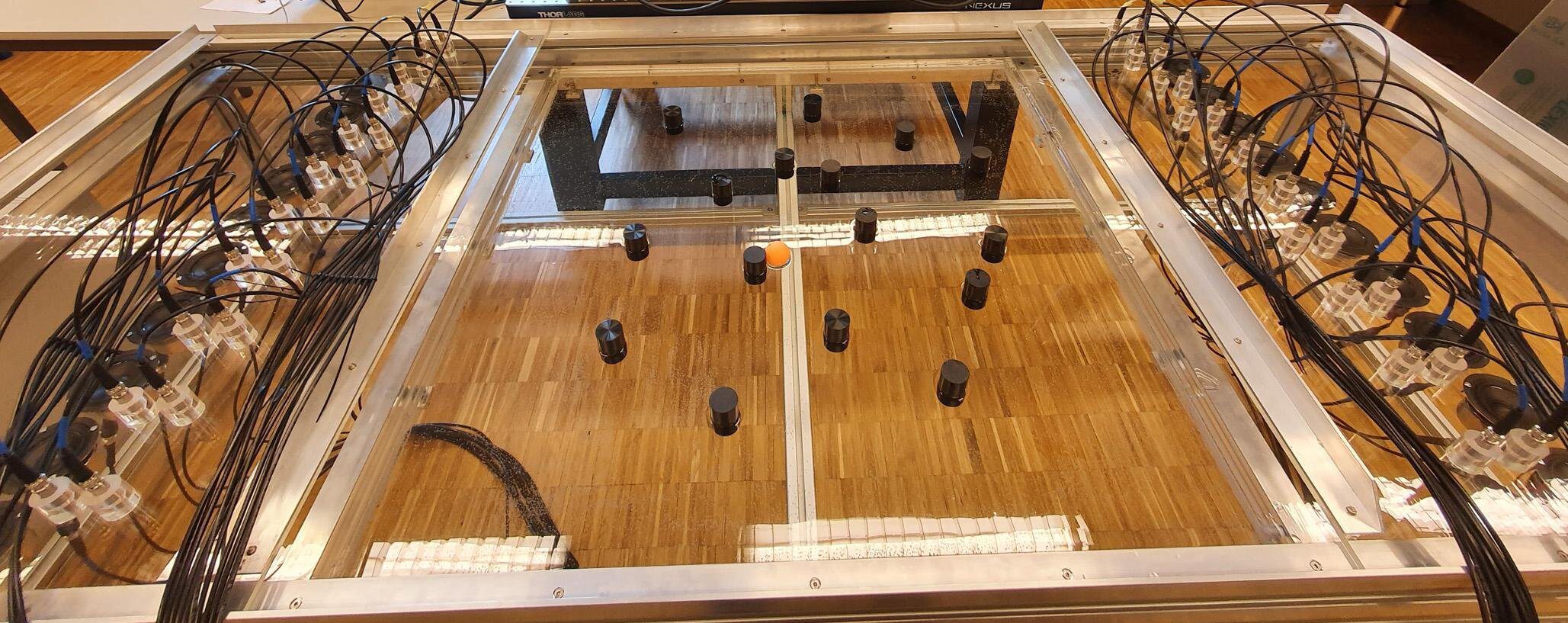 A imagem mostra o tanque com alto-falantes usado no experimento; no centro, é possível ver a bola laranja que foi movimentada por ondas sonoras.